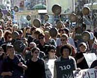 Women peace activists in Tel Aviv demonstrate wearing black T-shirts and banging pots and pans