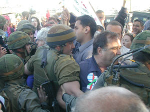 Peace activists stand chest-to-chest with Israeli soldiers, pushing against each other - photo by Elias I. Rishmawi