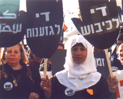 Israeli and Palestinian women hold signs in each others' languages saying End the Borders and End the Closure