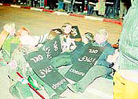 Women sitting and holding signs block the street by the Israeli Defense Ministry in Tel Aviv