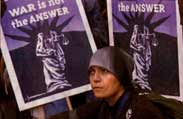 Woman standing in front of signs that say War Is Not the Answer