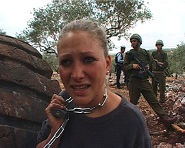 Yasmine with chain around her neck, mixed grief and horror on her face, soldiers and trees in background